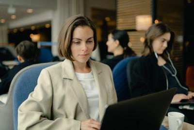 En kvinne med en datamaskin sitter på en flyplass